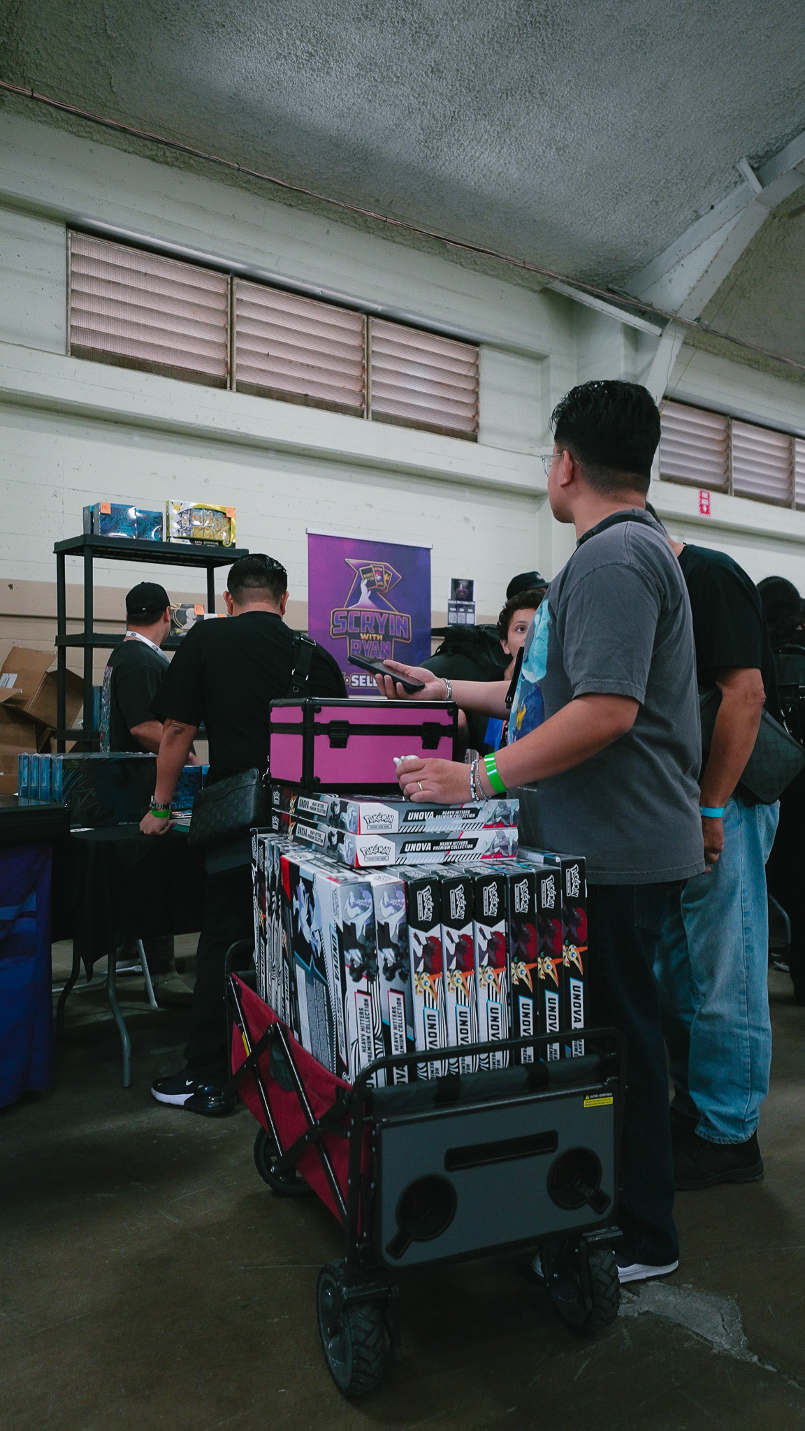 Attendee pulling a wagon stacked with Pokémon TCG box sets through the show floor