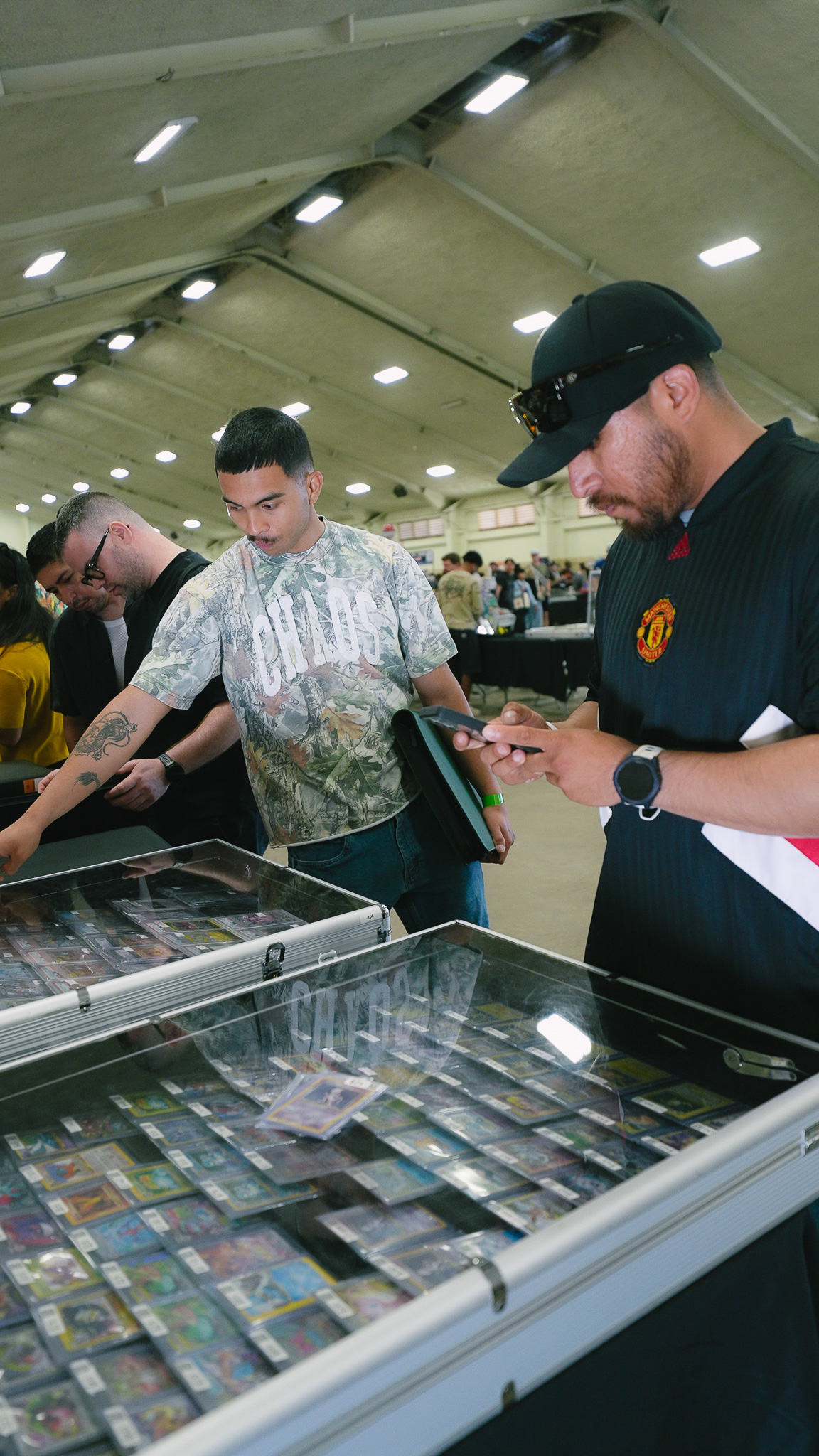Attendees examining graded cards in a glass display case at a vendor booth