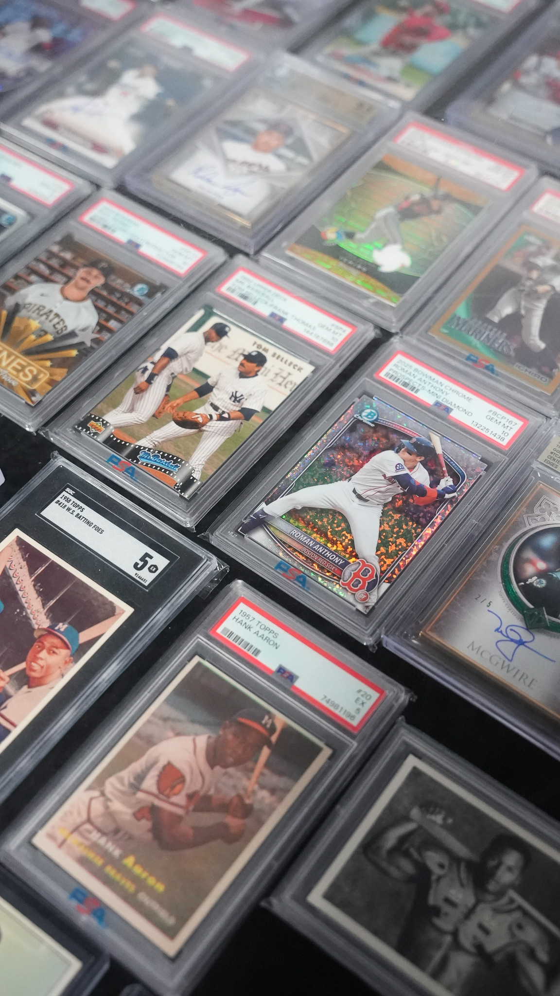 Close-up grid of graded baseball cards in display cases, including a vintage Hank Aaron card